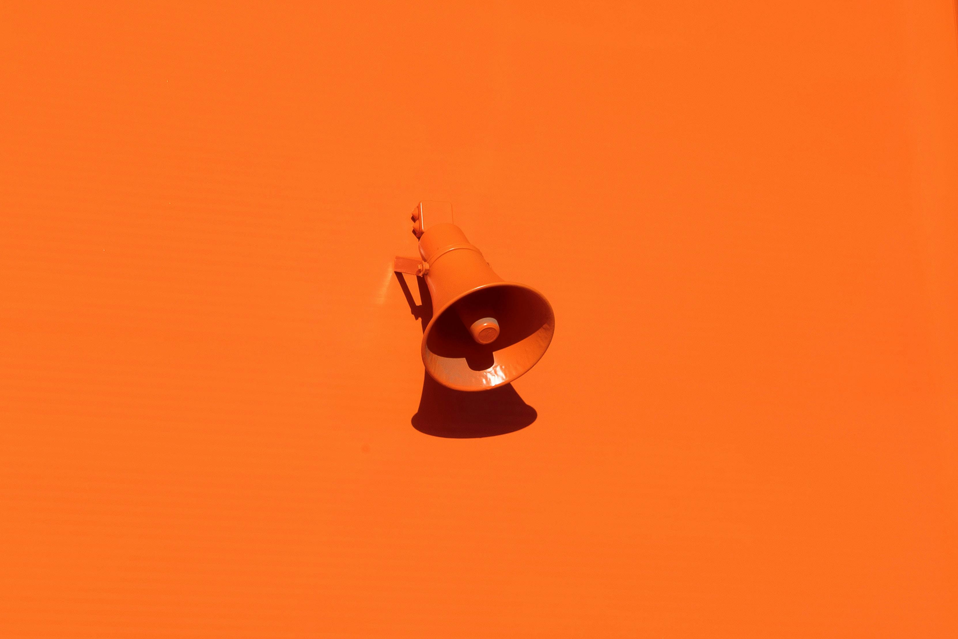 A 3D render of a megaphone on an orange background
